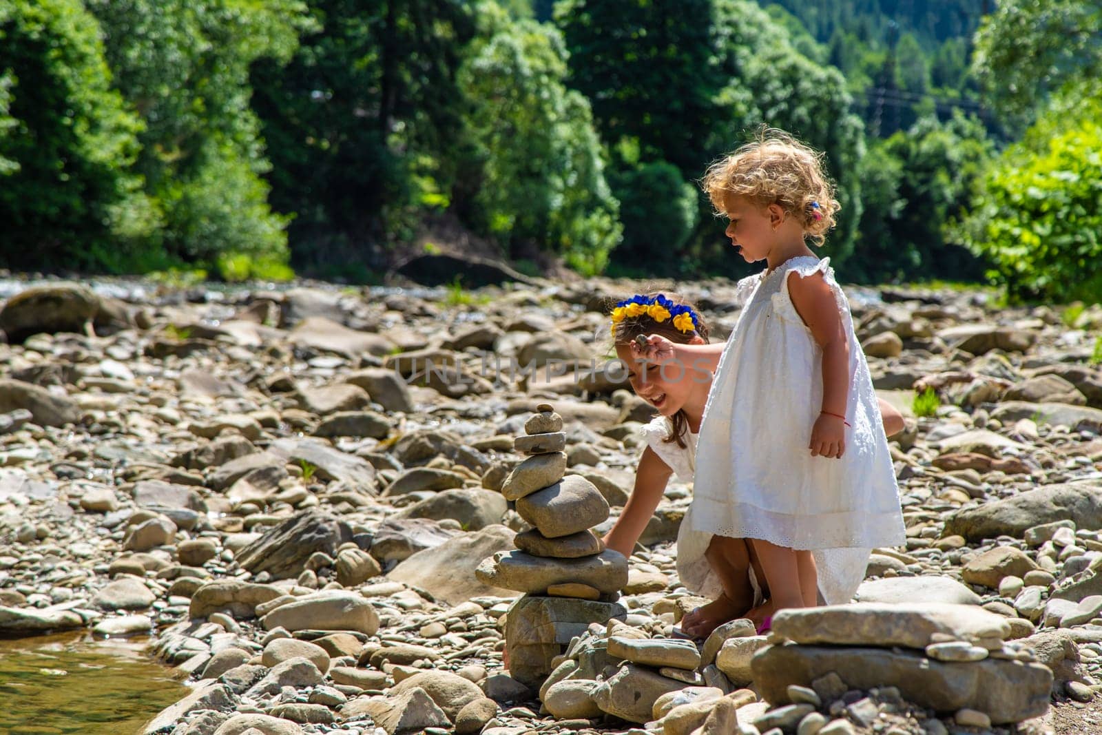 Children throw stones into the river. Selective focus. by yanadjana