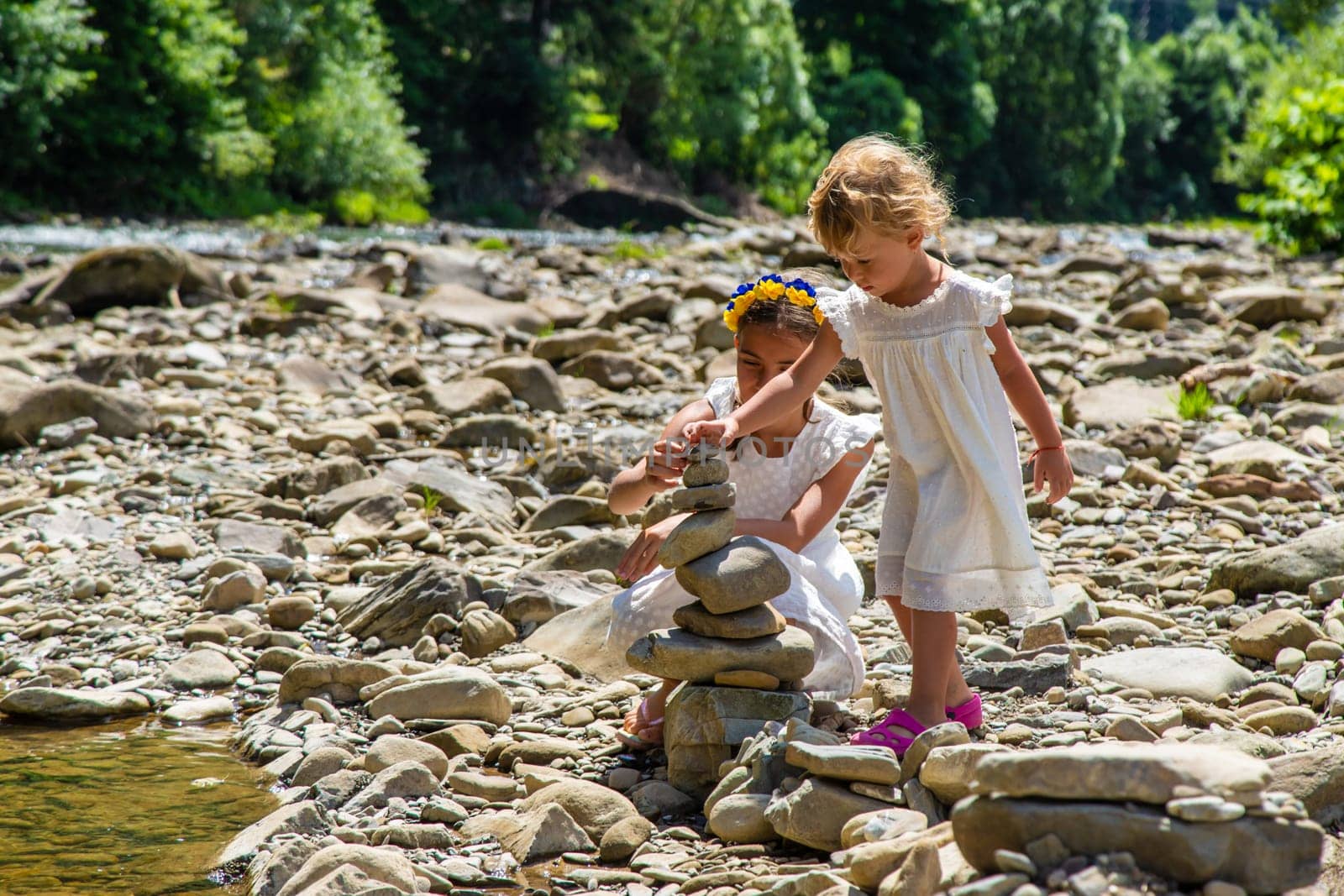 Children throw stones into the river. Selective focus. Kid.
