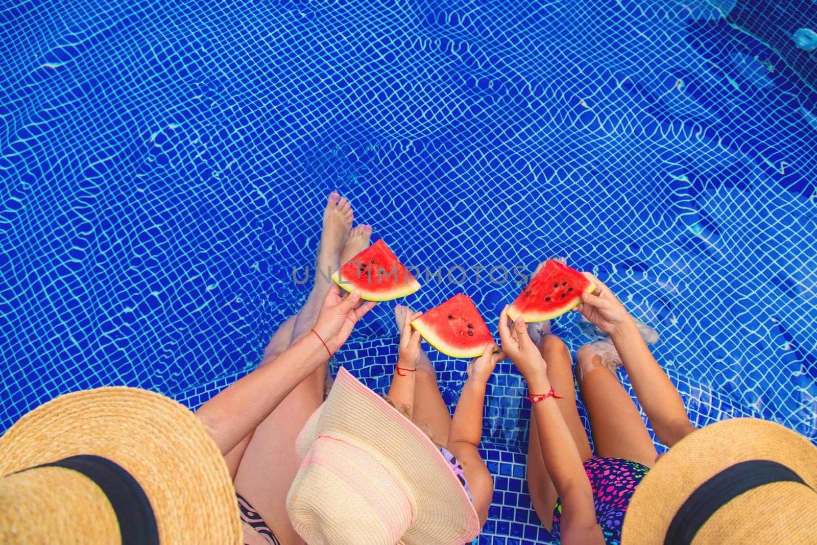 Children eat watermelon near the pool. Selective focus. Food.