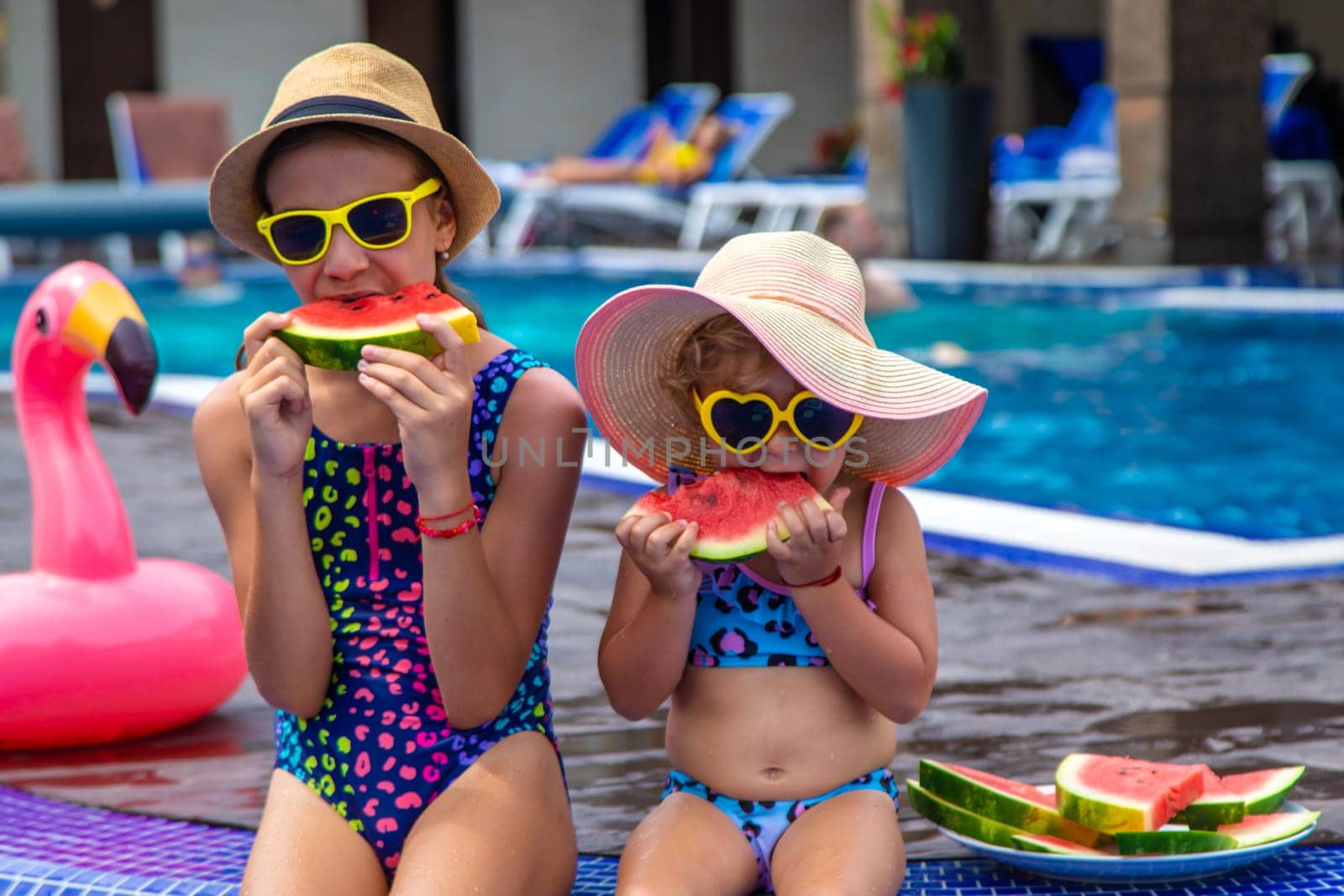 Children eat watermelon near the pool. Selective focus. by yanadjana