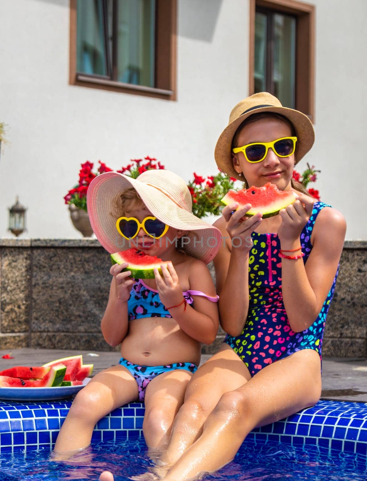 Children eat watermelon near the pool. Selective focus. Food.