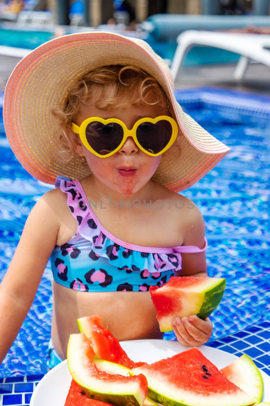 Children eat watermelon near the pool. Selective focus. by yanadjana
