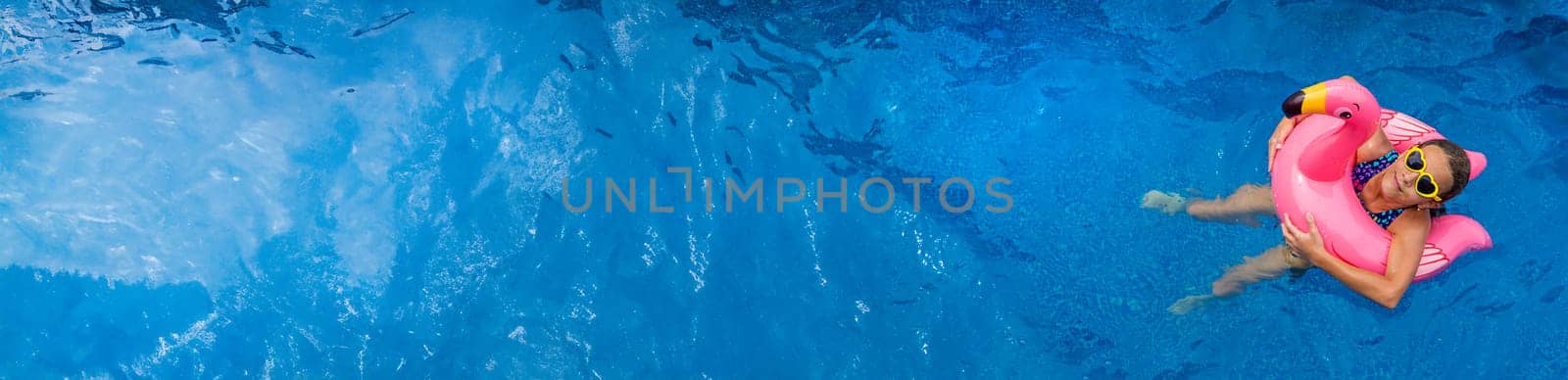 A child swims in a pool in a circle of flamingos. Selective focus. by yanadjana