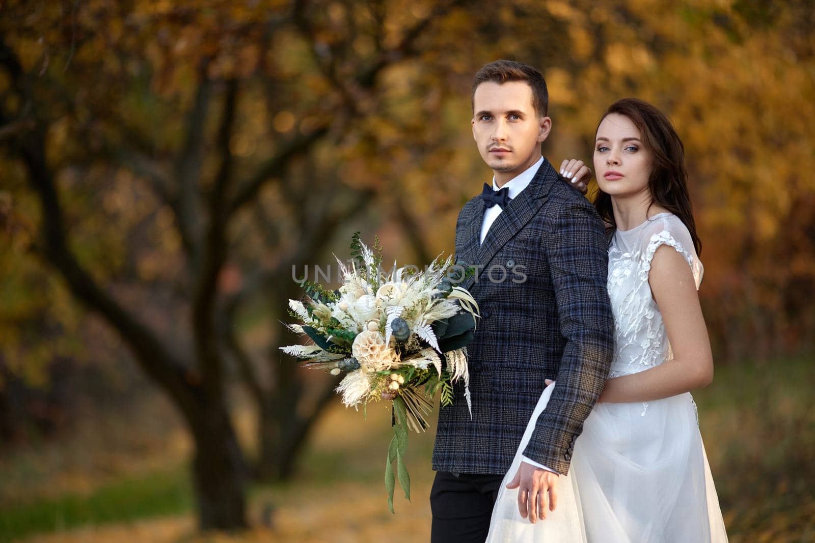 beautiful sensual bride in white wedding dress and groom standing outdoor on natural background
