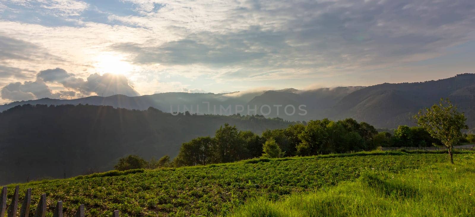 beautiful countryside and cloudy sky with sun rays between clouds