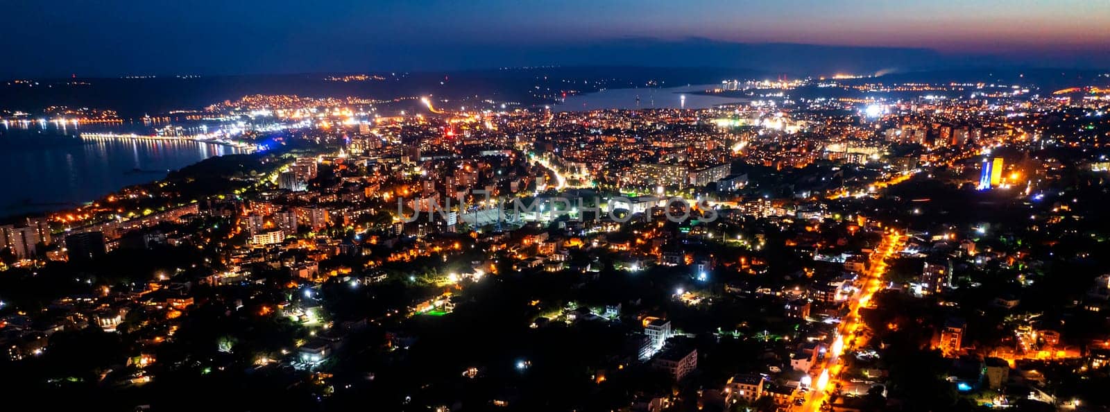 A panoramic aerial view of the city near the sea at night. 