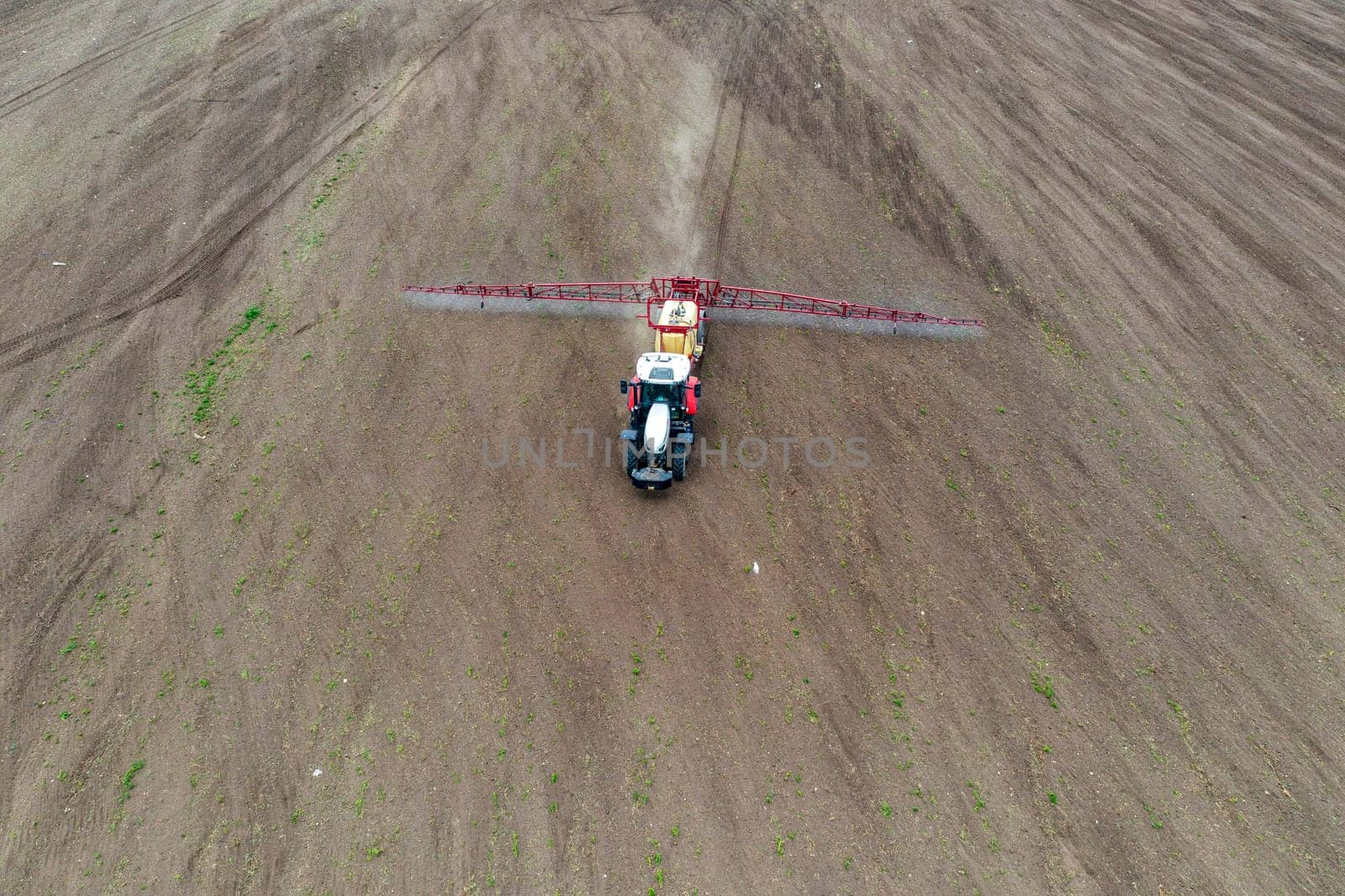 Top view of tractor spraying grain on a field. by EdVal