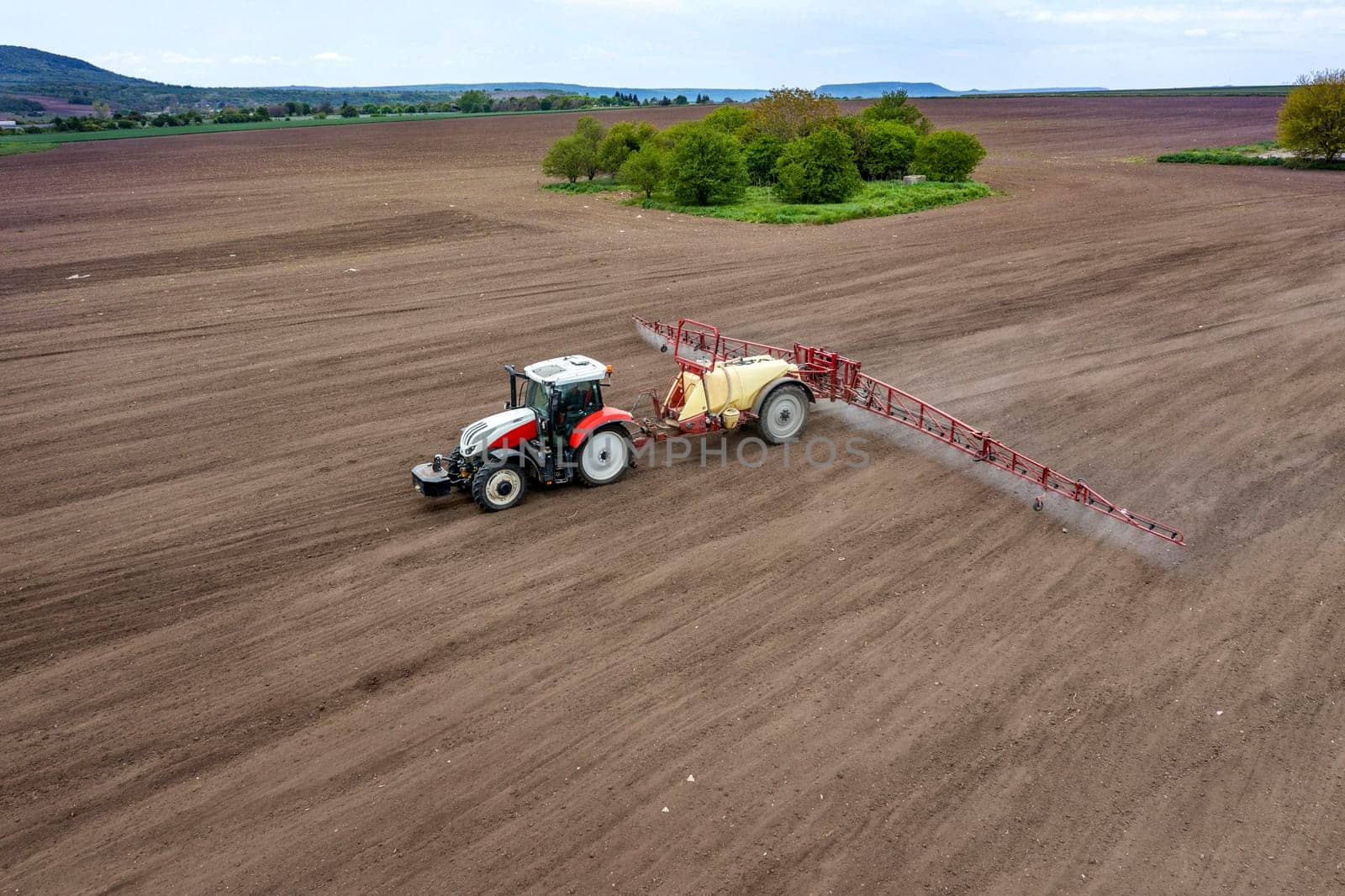 Aerial view of field and tractor spraying grain by EdVal