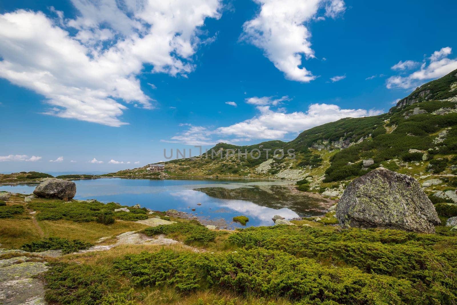 Landscape with mountain lake and big rock.