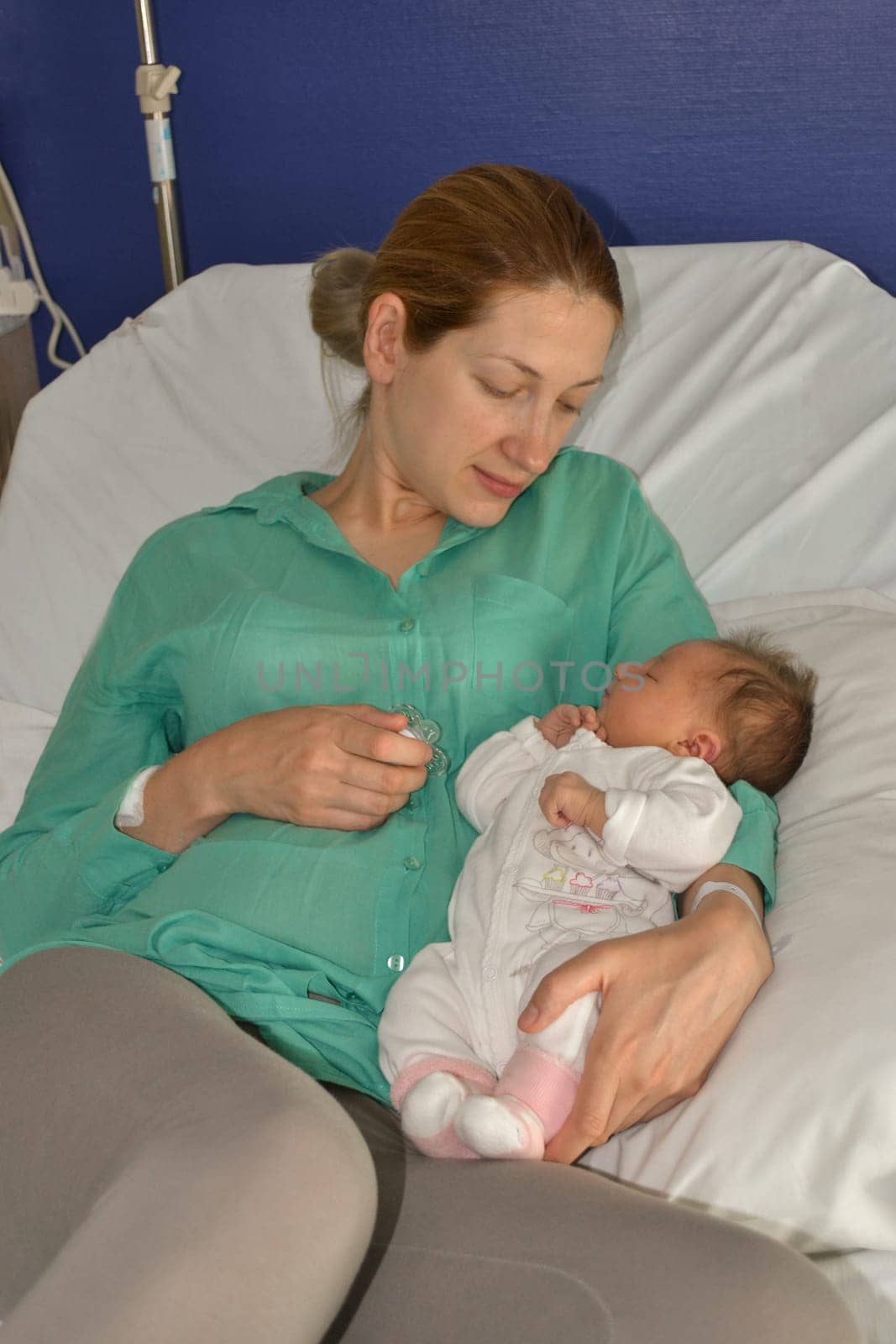 A mother looks at her newborn baby at a hospital.