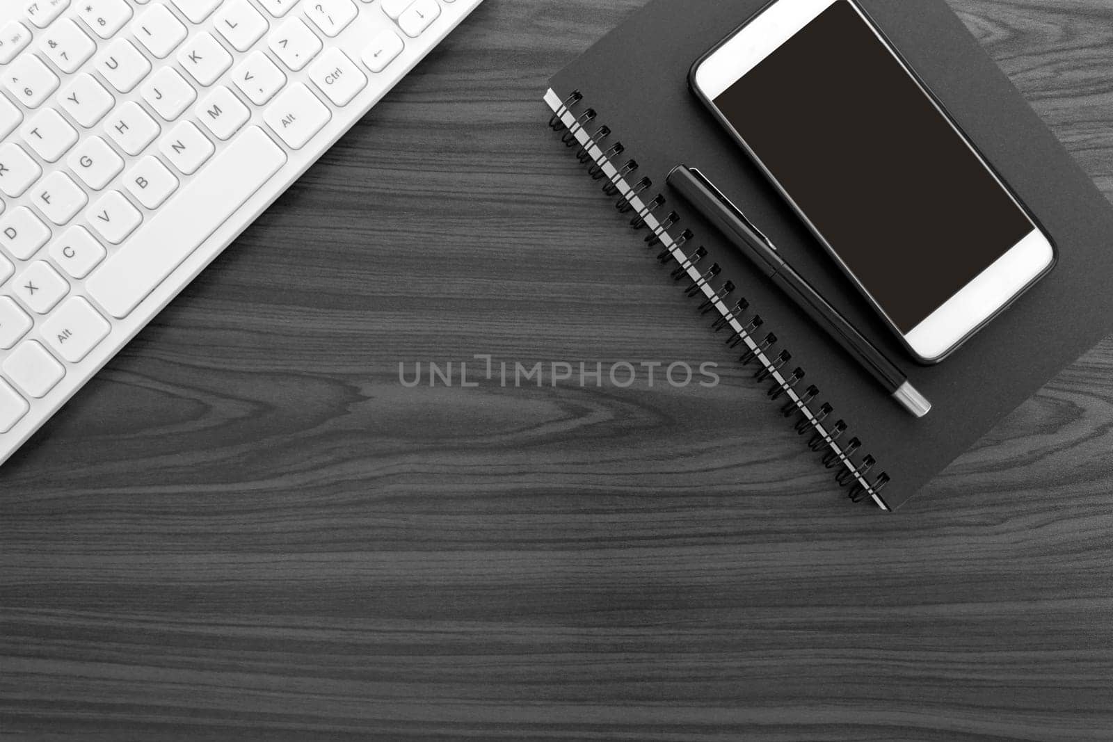 Home office workspace with white keyboard, note books, pen and smartphone. Flat lay, top view. Copy space.