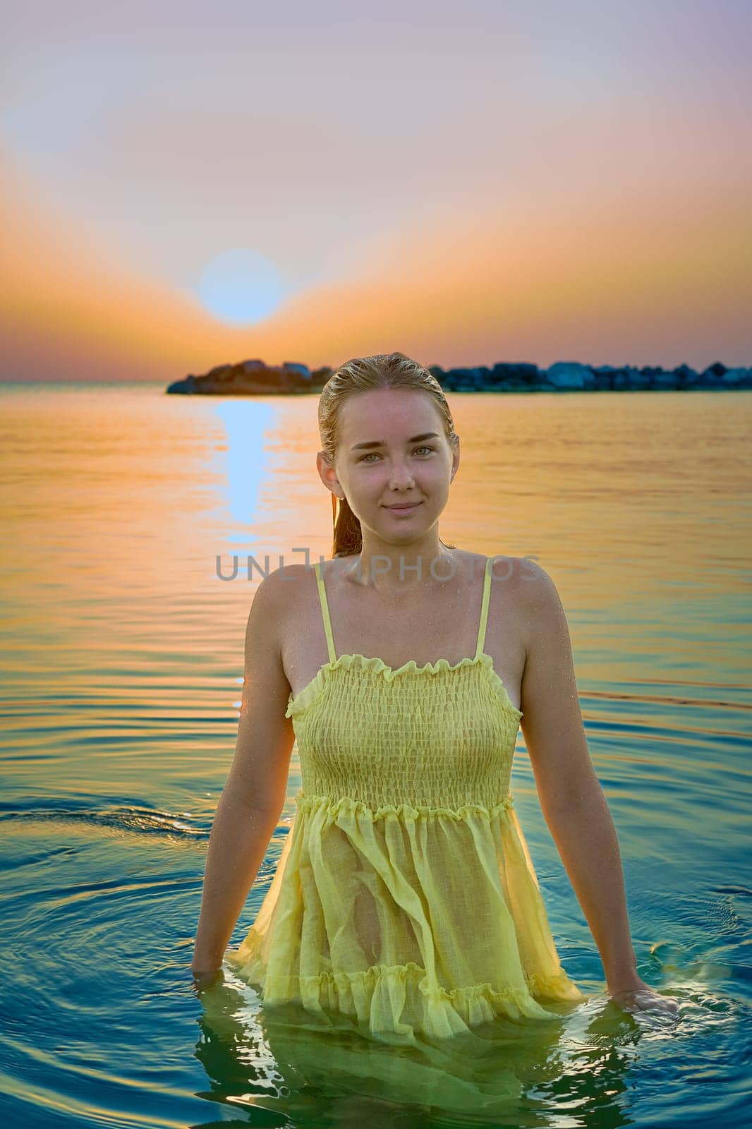 Young woman feeling good after morning swim and relaxing on the beach at sunrise