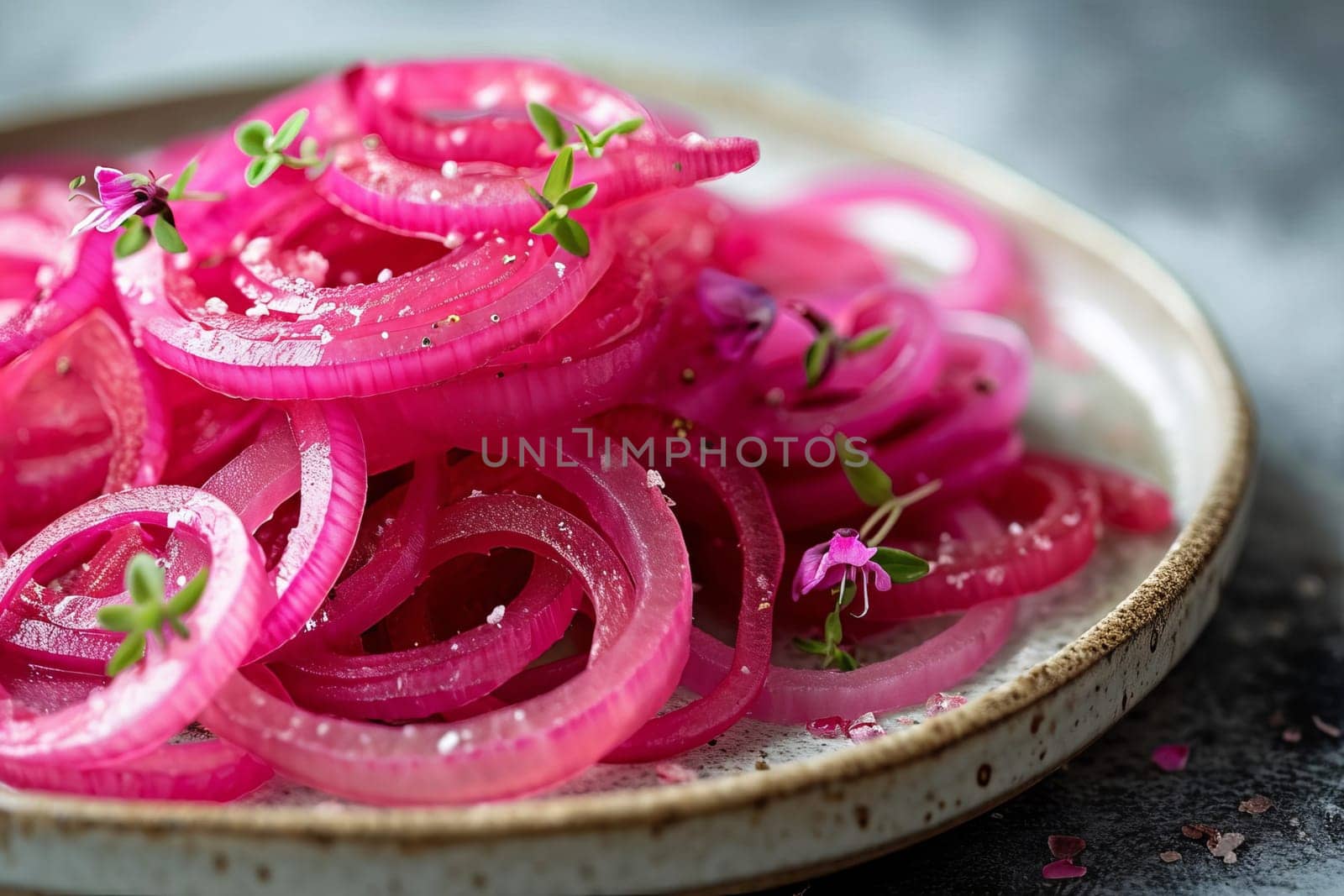 Red pickled onion rings lie on a gray background. Selective focus.