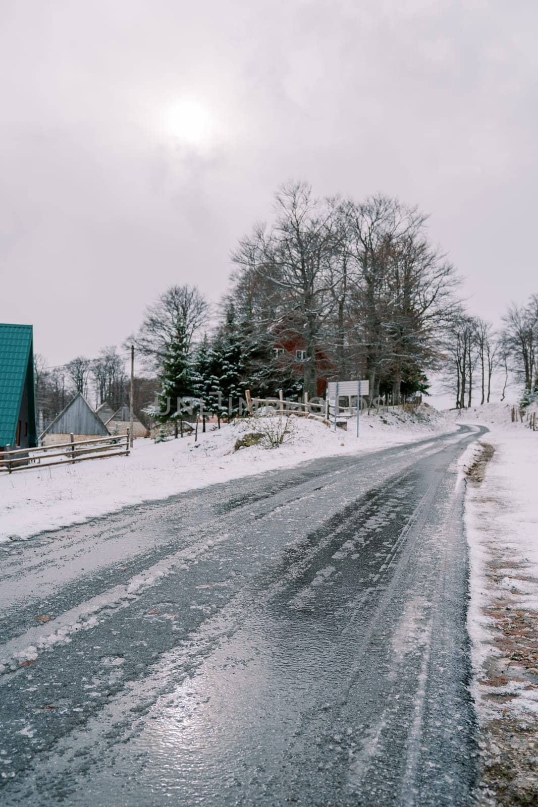 Icy road in a snowy village with cozy houses. High quality photo