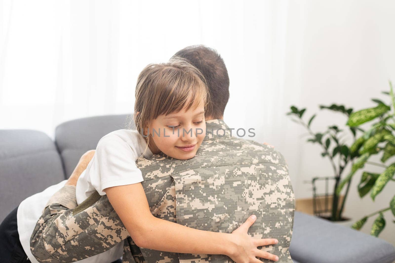 Young man in military uniform with his wife on sofa at home by Andelov13