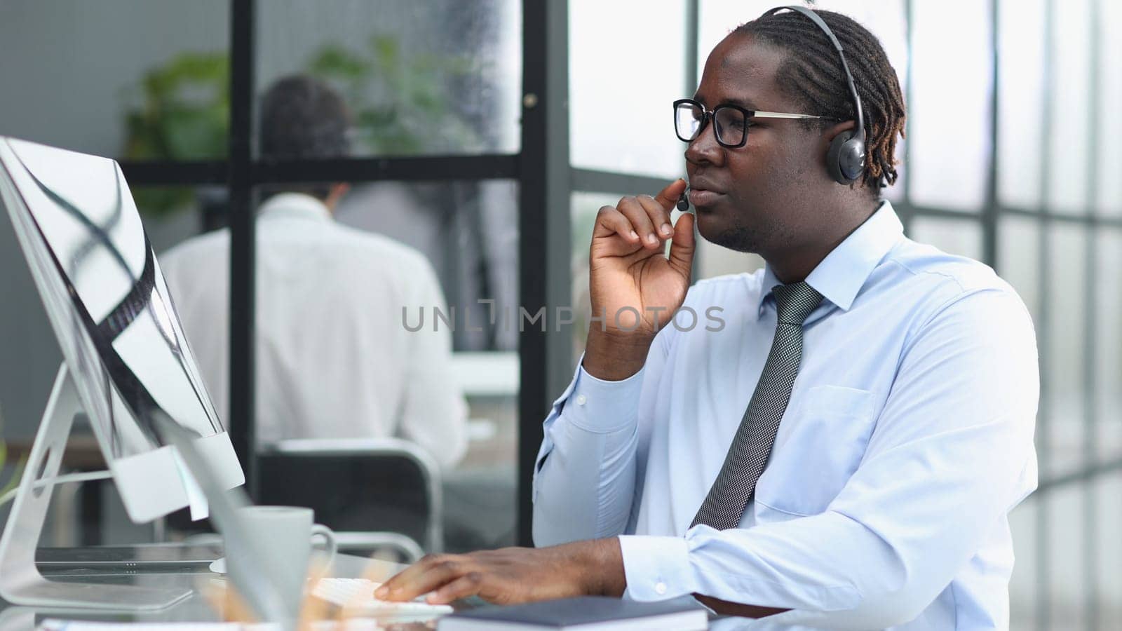 a man at a workplace at a table in front of a computer in a call center