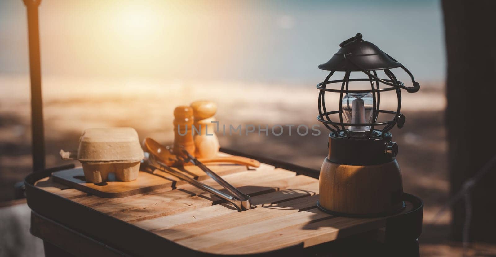 Old meets new on the campsite, A vintage kerosene lamp and a modern LED lantern on a wooden table. The perfect summer setup for camping and picnics. Illuminate your environment.