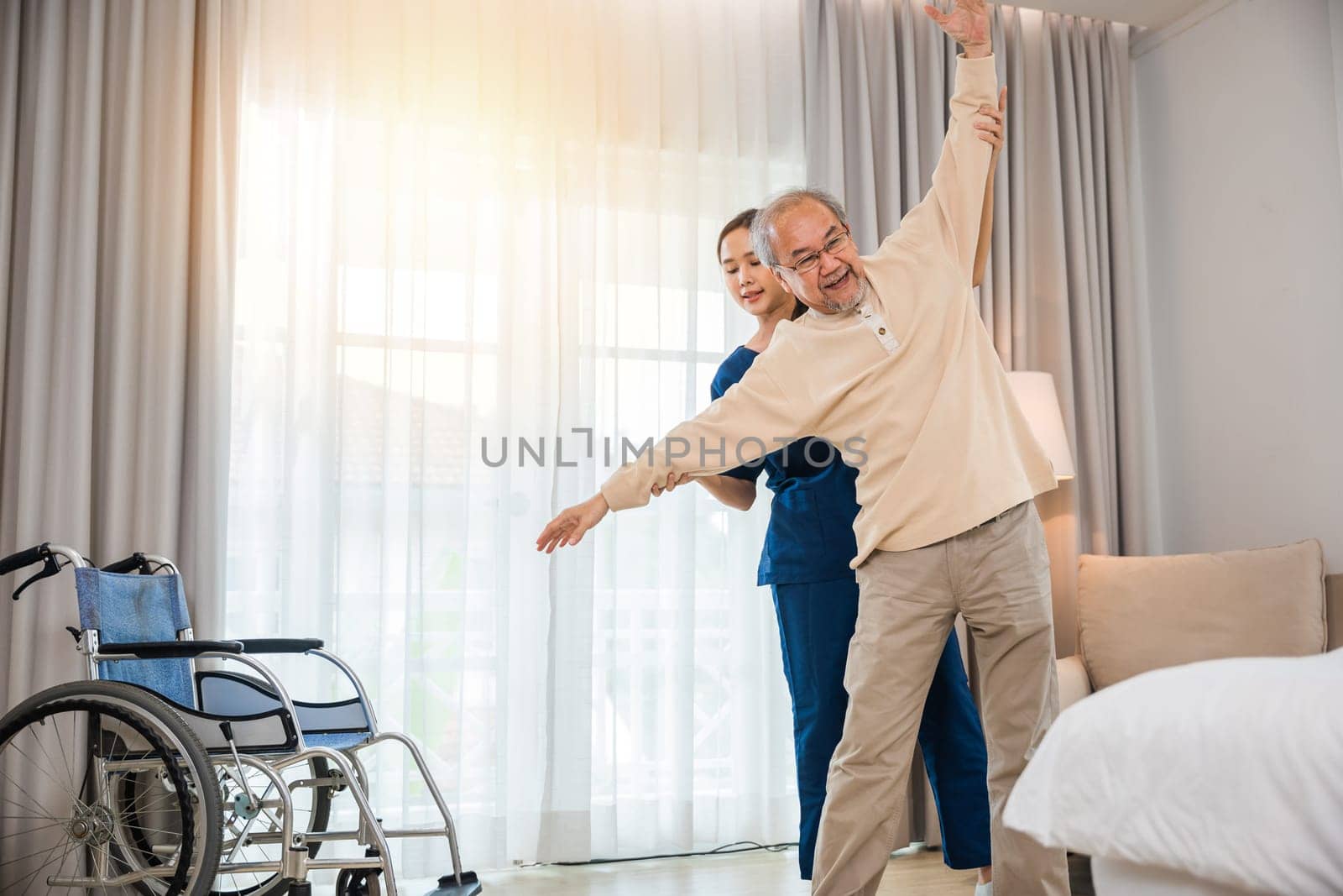 Old senior man enjoys training with physiotherapist for outstretched arms at home by Sorapop