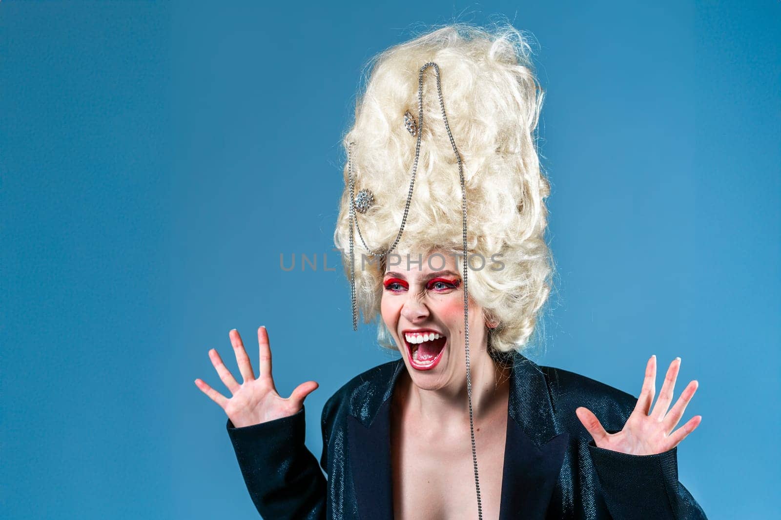 Weird yelling princess, queen wearing black jacket, and vintage royal wig with red makeup scream isolated on blue background. Concept of comparison of eras, modernity and renaissance, beauty