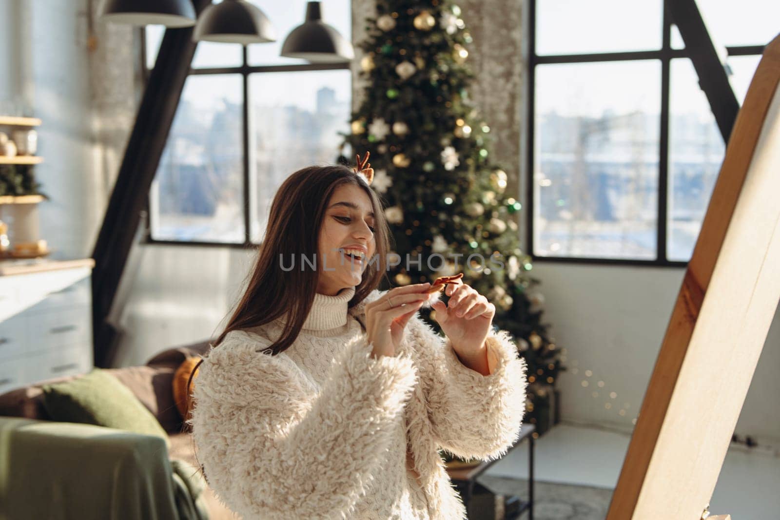 With a merry spirit, a bright young woman wearing a Christmas reindeer mask lights up the apartment with her smile. High quality photo