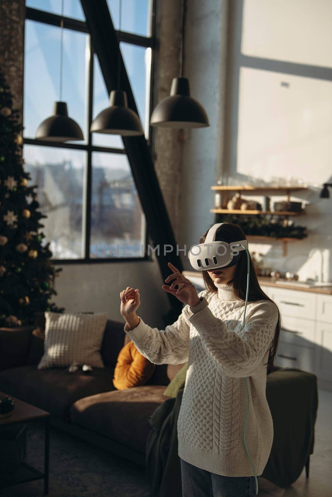Using a virtual reality headset, a lovely young woman engages in an online game in her apartment. High quality photo