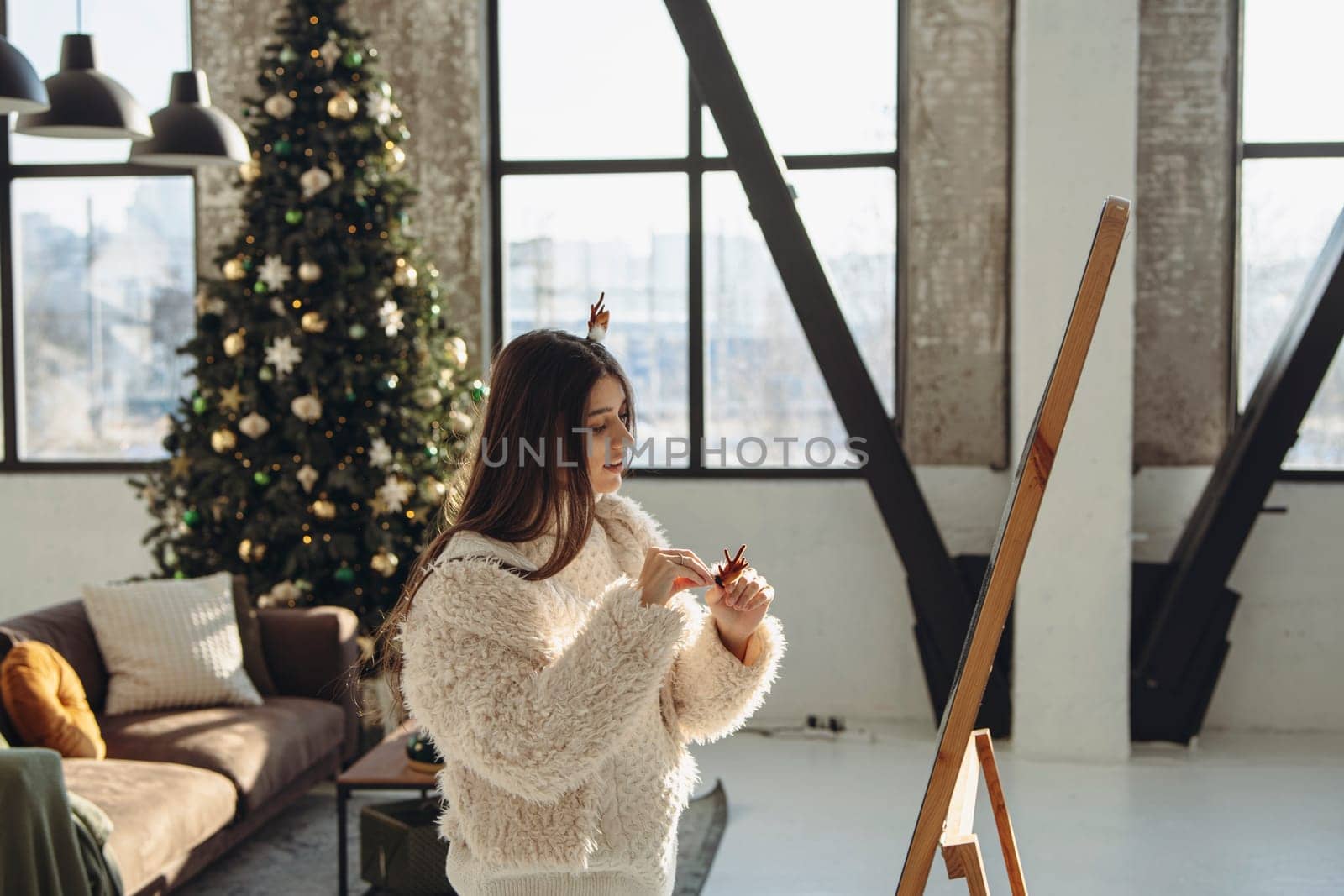 Radiating happiness, a vibrant young lady wearing a Christmas reindeer mask beams in the apartment. High quality photo