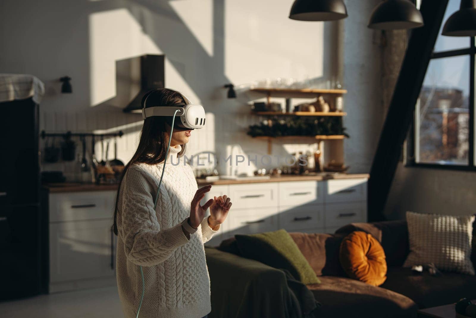In the comfort of her apartment, a stunning young lady plays an online game with a VR headset. High quality photo
