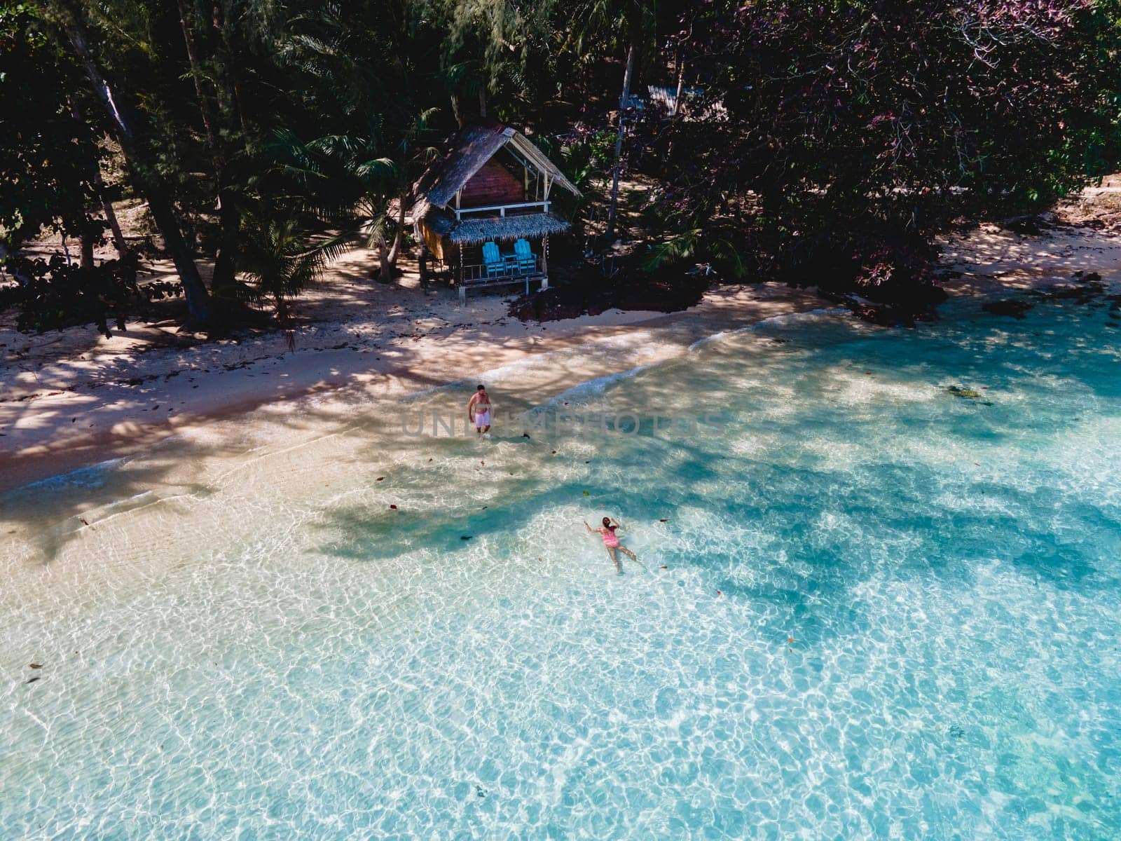 Koh Wai Island Trat Thailand, wooden bamboo hut bungalow on the beach. a young couple of men and woman on a tropical Island in Thailand swimming in a turqouse colored ocean