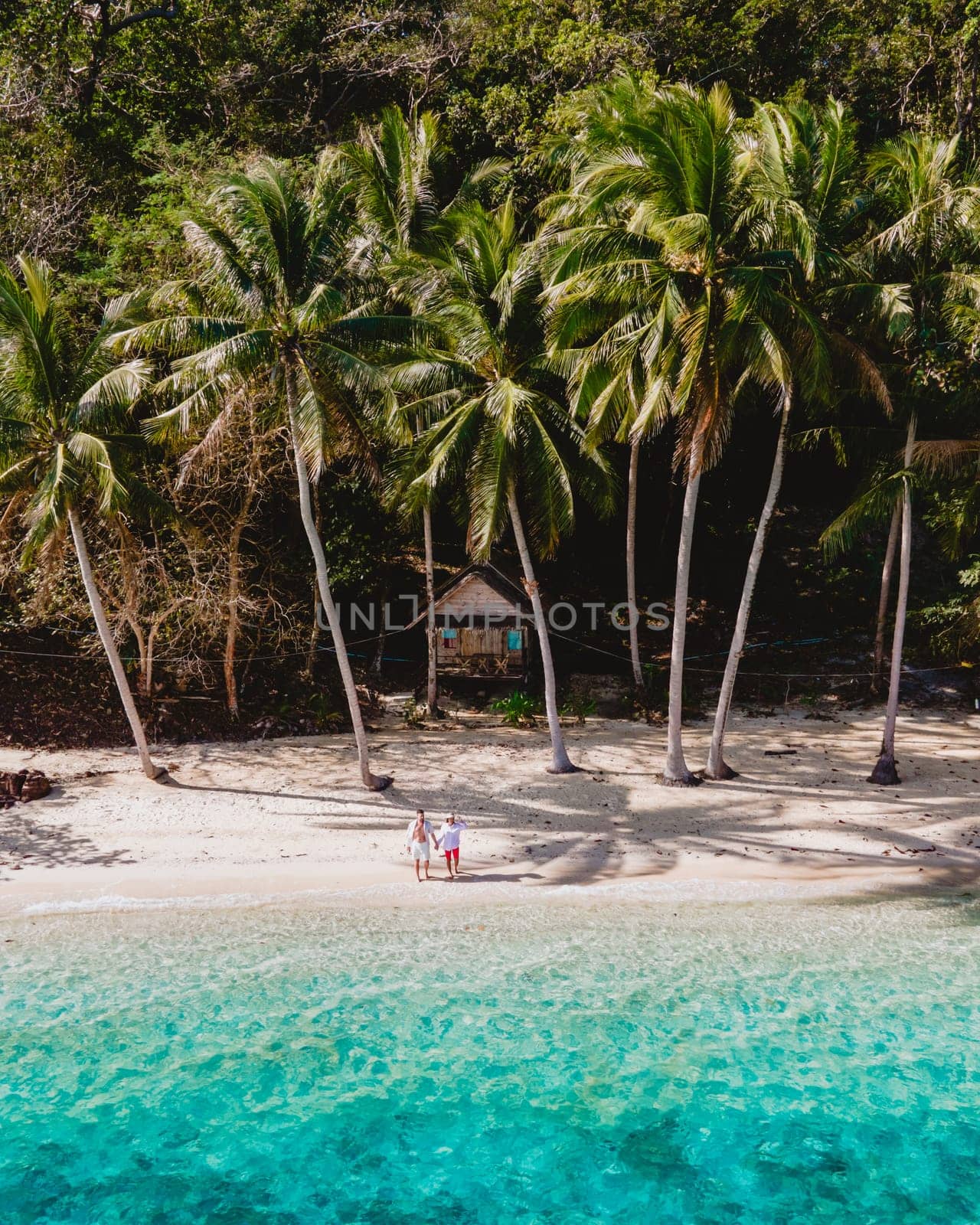 Koh Wai Island Trat Thailand, wooden bamboo hut bungalow on the beach. a young couple of men and woman on a tropical Island in Thailand with palm trees on the beach and turqouse colored ocean