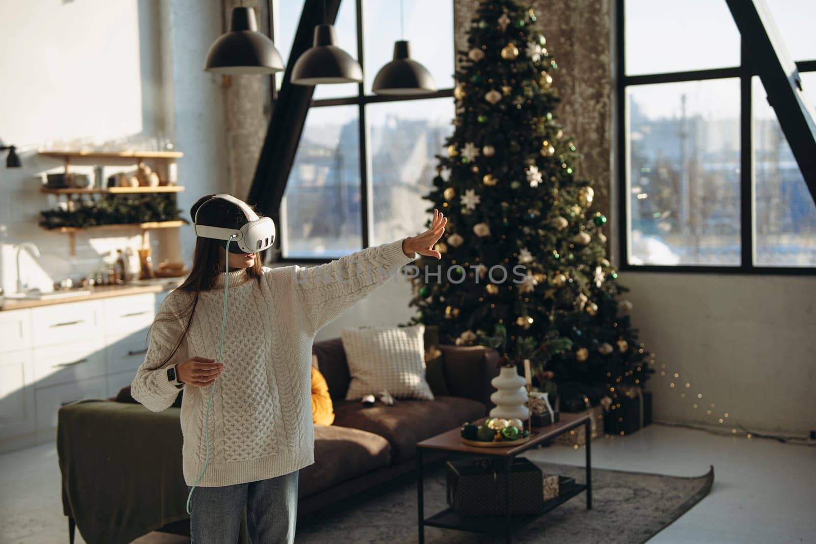 Using a VR headset, a beautiful young woman plays an online game comfortably in her apartment. by teksomolika