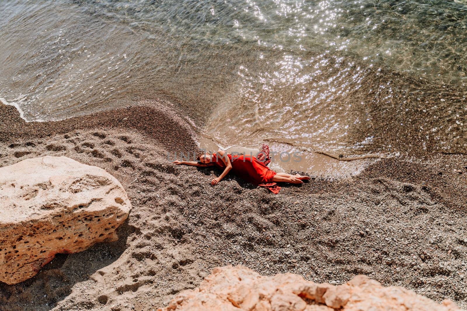 Woman red dress sea. Female dancer in a long red dress posing on a beach with rocks on sunny day by Matiunina