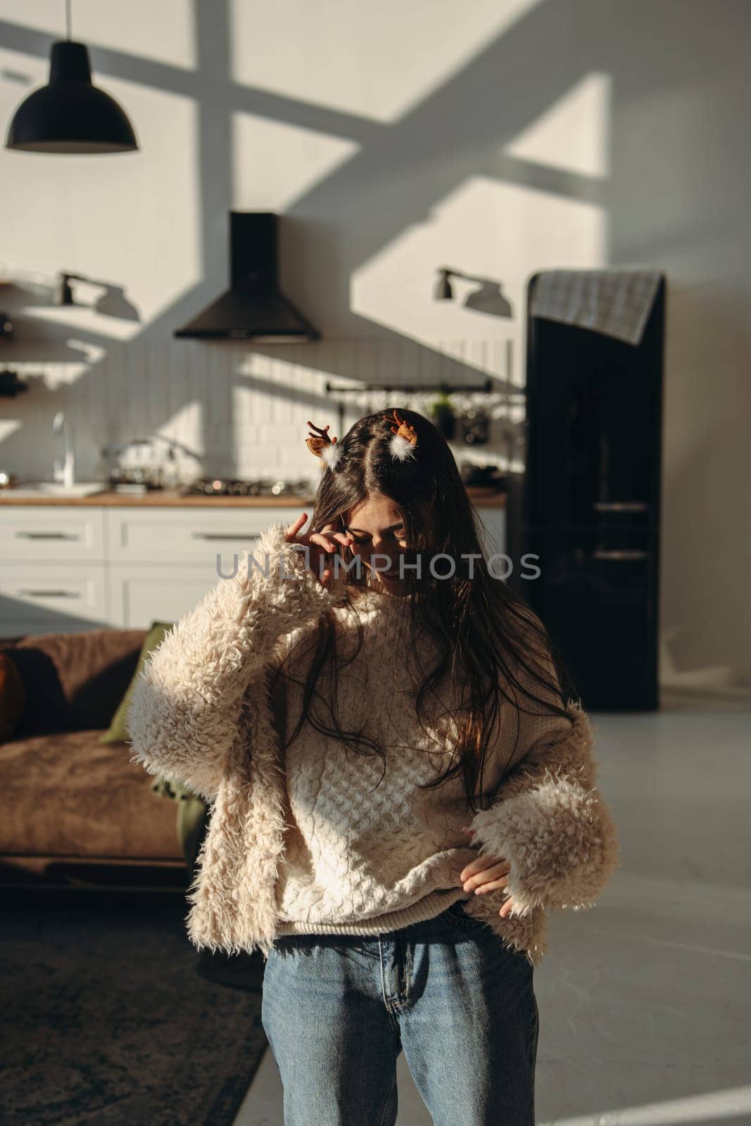 With sunlight streaming in, a vibrant young woman wears a Christmas reindeer mask. High quality photo