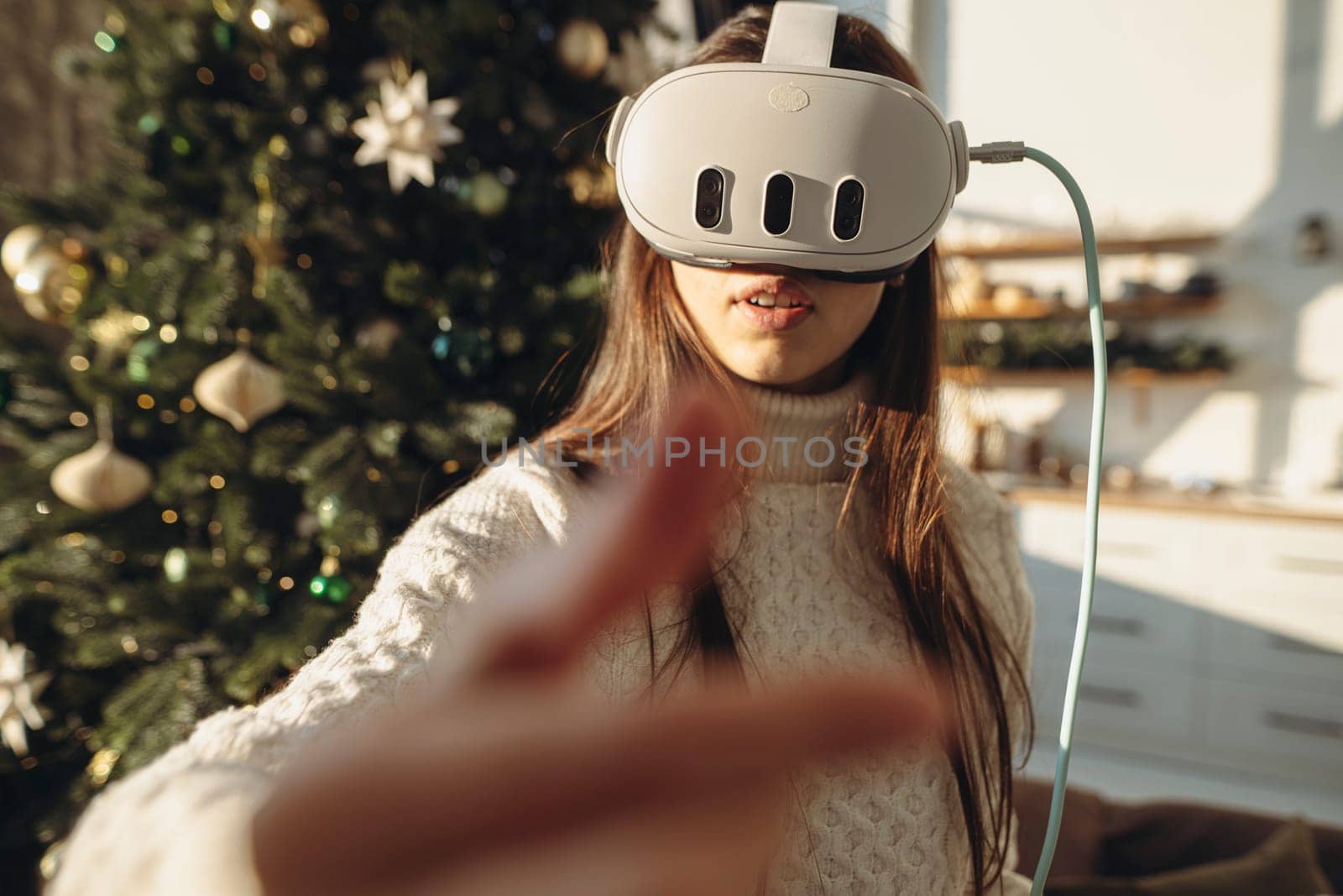 A portrait showcasing a beautiful girl with a VR headset against the festive backdrop of a Christmas tree. High quality photo