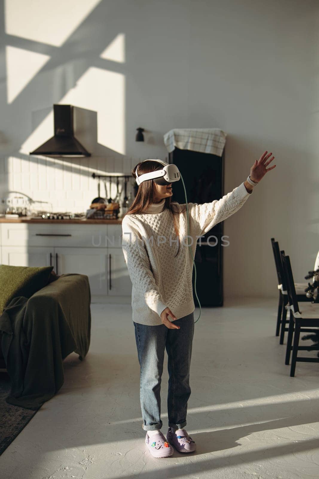 Playing an online game, a lovely young lady enjoys her VR headset in the apartment. High quality photo