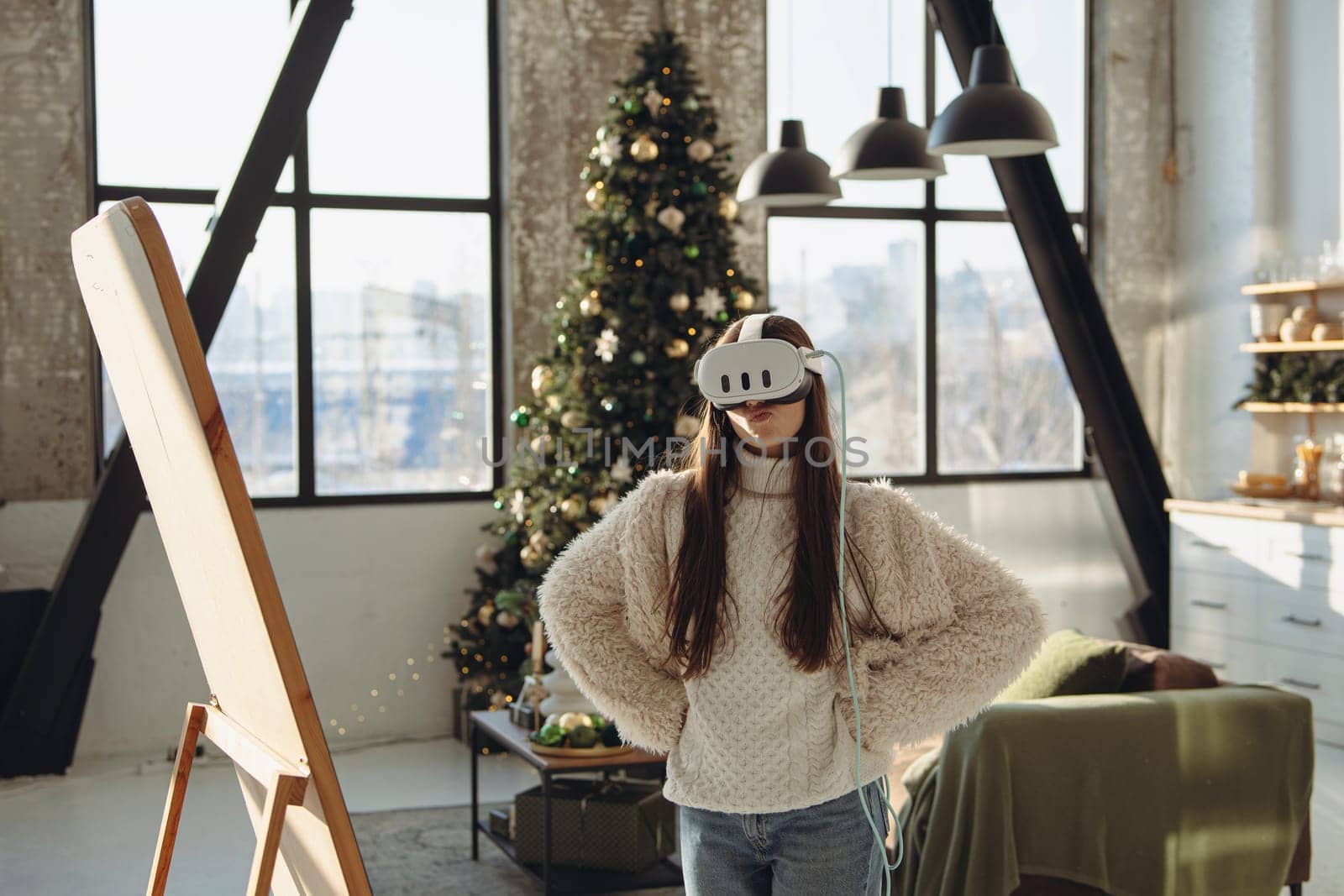 With a Christmas tree as a backdrop, a lovely young lady engages in virtual reality. High quality photo