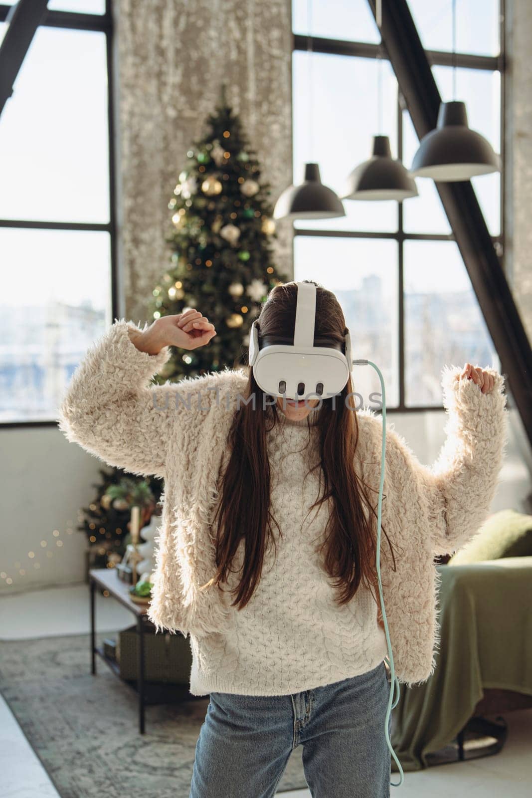 Engaged in virtual reality, a stunning young woman stands near a Christmas tree. High quality photo