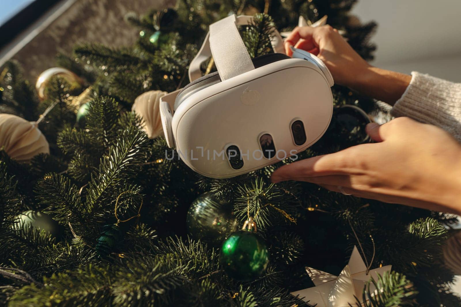 With a Christmas tree in the background, a girl is holding a virtual reality headset. High quality photo