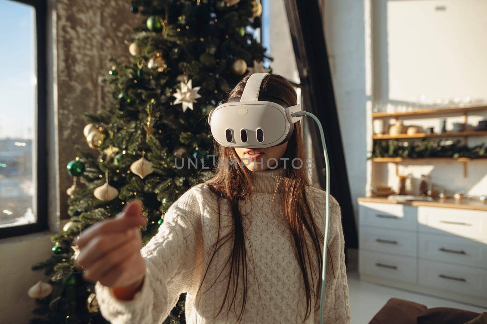 A portrait of a lovely girl in a virtual reality headset with a Christmas tree in the background. High quality photo
