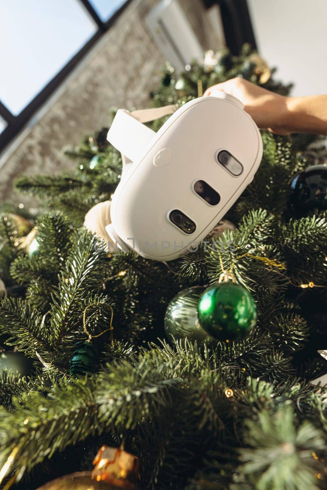 A Christmas tree forms the background as a girl holds a virtual reality headset. by teksomolika