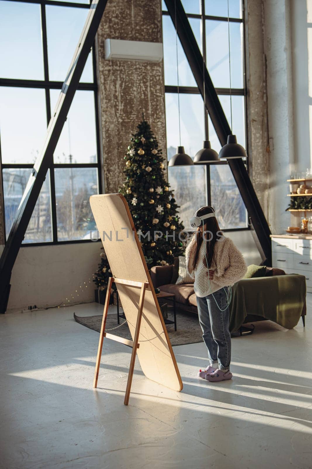 Embraced by the Christmas atmosphere, a young woman in light attire and a VR headset stands before the mirror. High quality photo