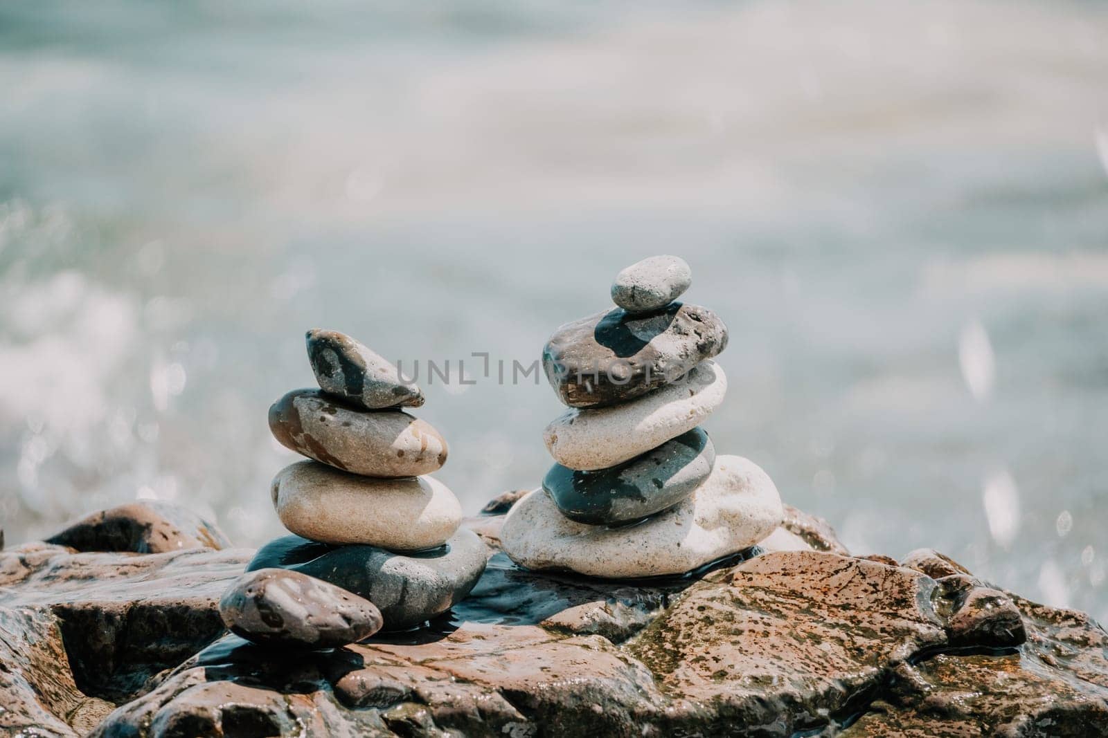 Balanced rock pyramid on pebbles beach, sunny day and clear sky at sunset. Golden sea bokeh on background. Selective focus, zen stones on sea beach, meditation, spa, harmony, calm, balance concept. by panophotograph