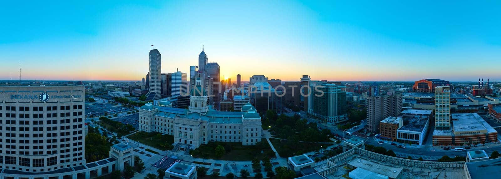 Sunrise over Indianapolis skyline, showcasing a blend of modern and historical architecture from an aerial perspective, captured by drone in 2023
