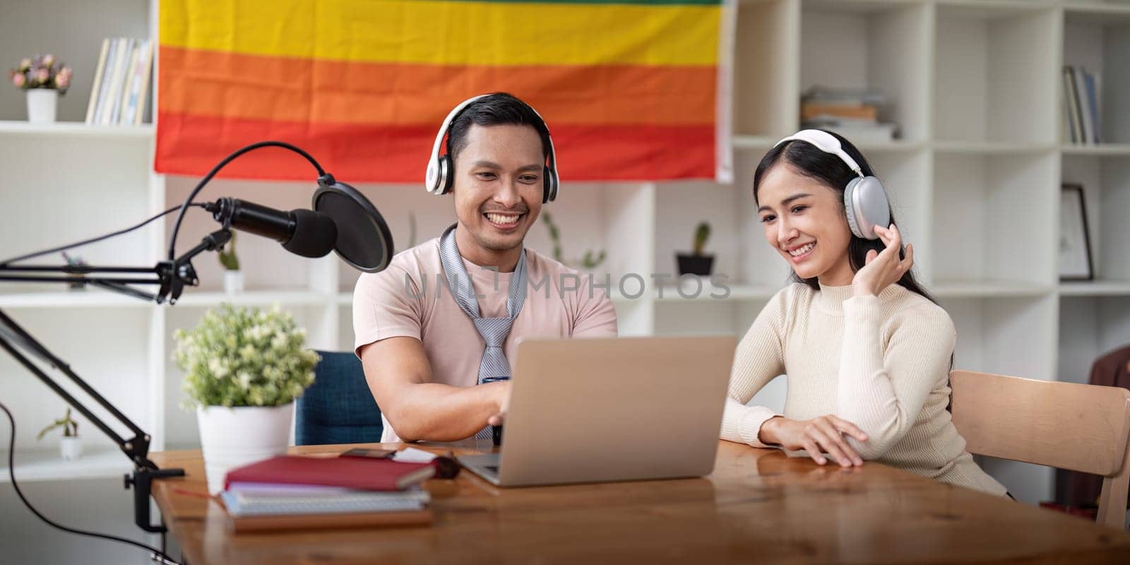 Asian gay radio host enjoy chatting while record an audio podcast with female friend.