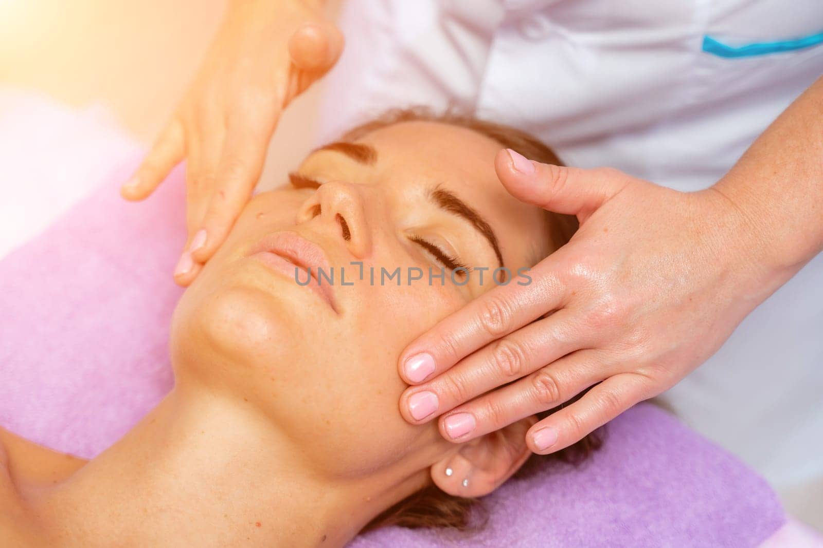 Relaxing massage. European woman getting facial massage in spa salon, side view by Matiunina