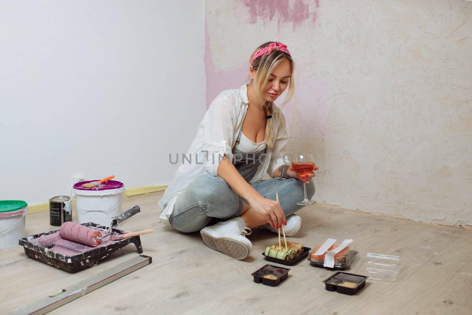 Sexy girl designer eats sushi on the construction site. painter has lunch after work. Concept interior design and room repair.