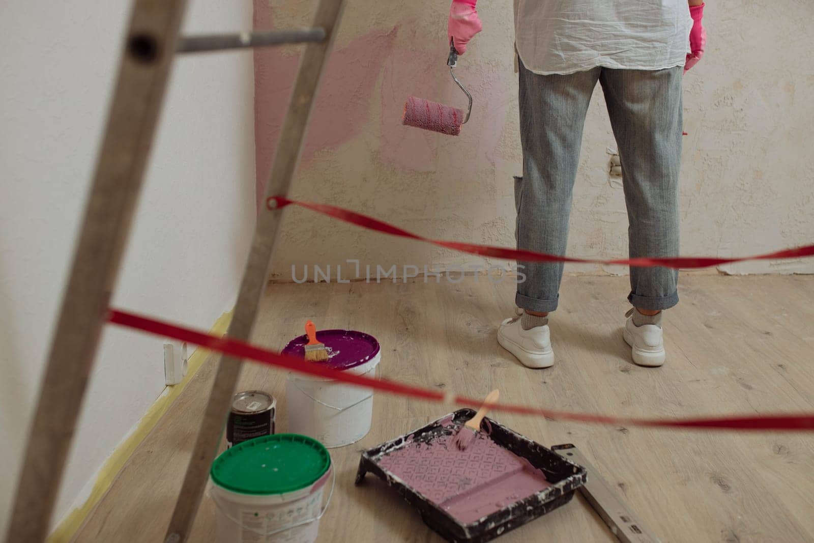 Young woman with the roller painting the wall in new house.