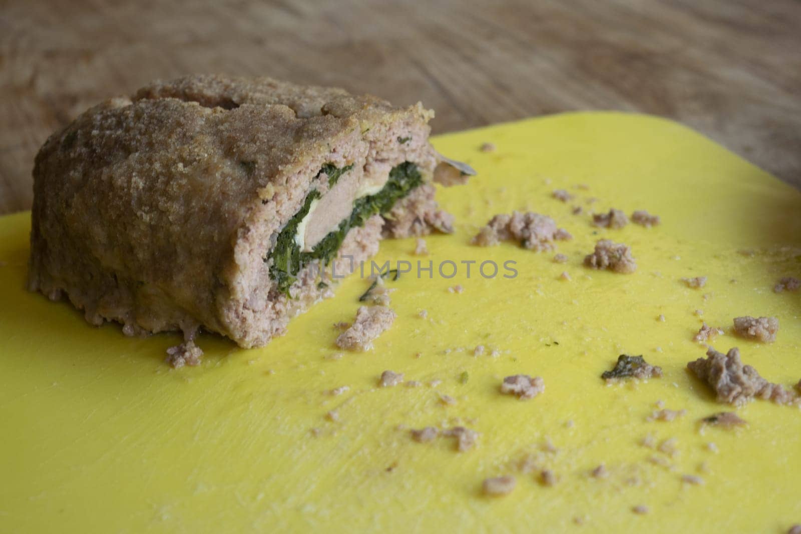 spinach meatloaf cut in half placed on a yellow cutting board