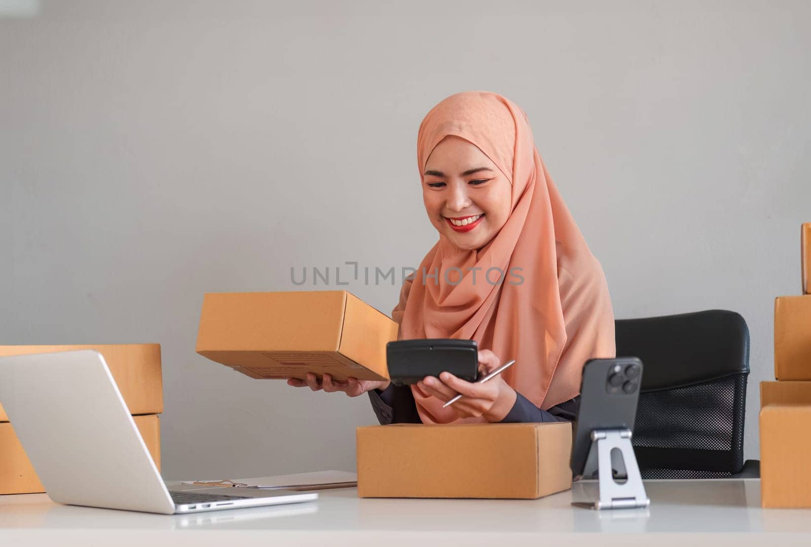 Asian Muslim businesswoman checks stock orders and saves them on her home office laptop. small business owner Shipping in online markets The concept of freedom in life by wichayada