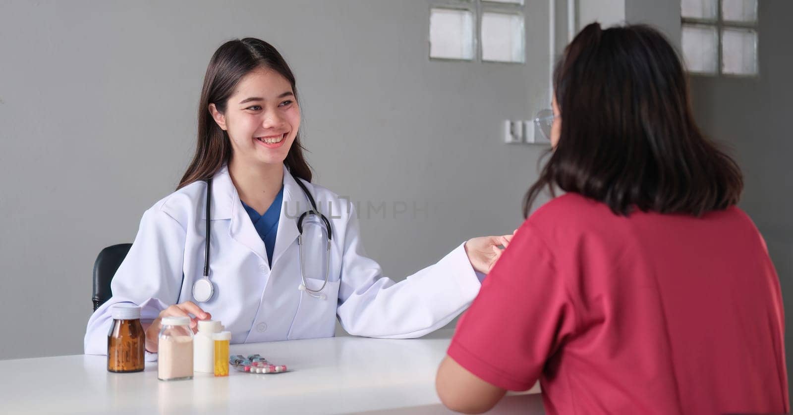 An Asian female doctor is consulting a patient who comes to discuss taking medication for health care. and treat disease with medicine.