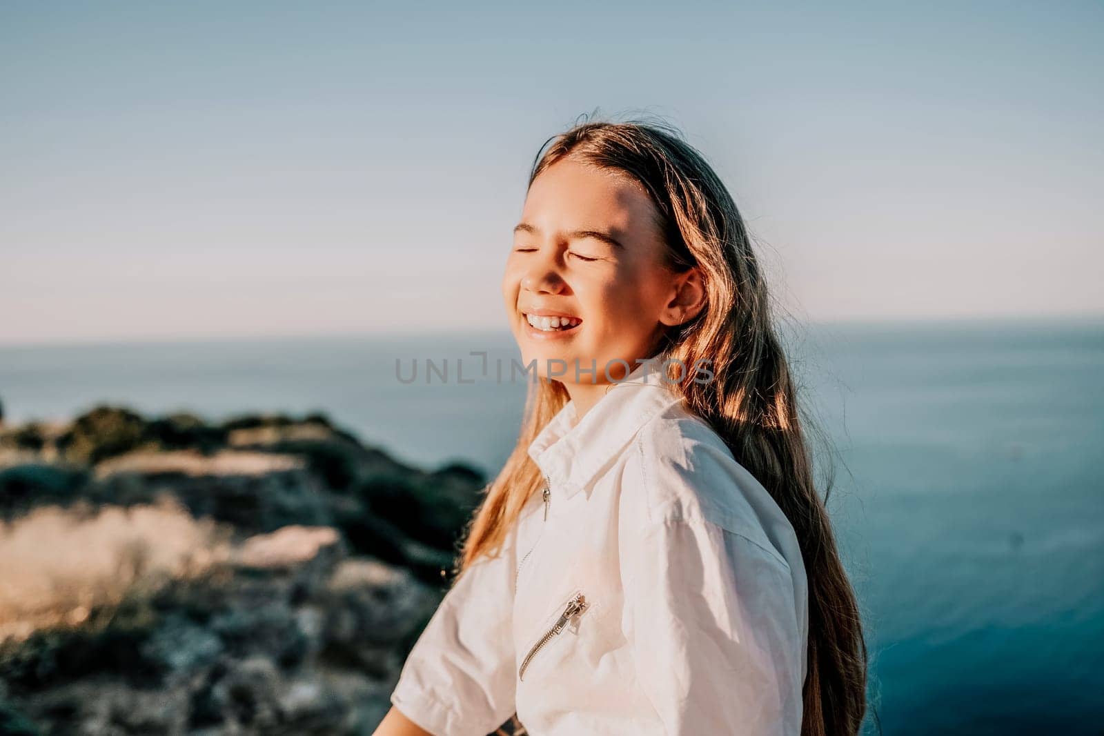Adorable teenage girl outdoors enjoying sunset at beach on summer day. Close up portrait of smiling young romantic teenager girl with long hair on beach at summer evening. Travel and holidays by panophotograph